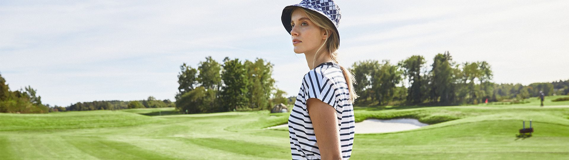 Spring Summer 2024 kollektionen, kvinna på green iklädd blå golfkläder med randig golftopp